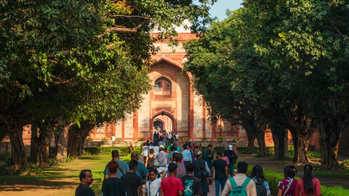 People walking towards an ancient arched building entrance